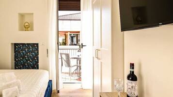 Habitación de hotel con cama, escritorio, botella de vino, copas y bandeja de aperitivos.