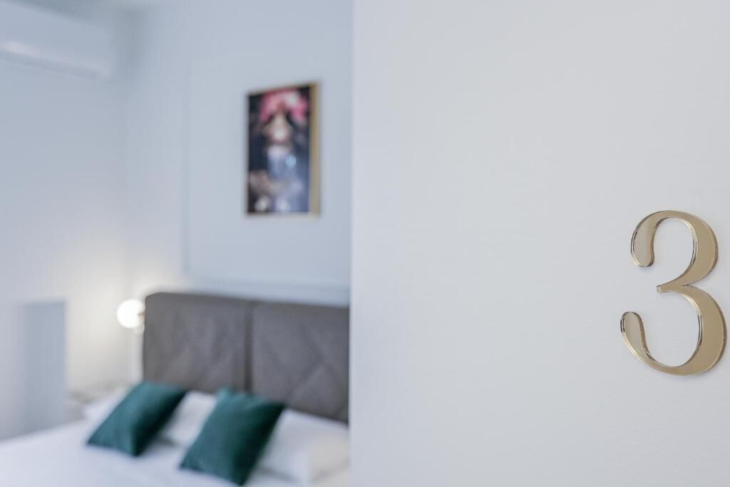 Una camera d'albergo con un letto, una testiera e il numero '3' montato a parete.