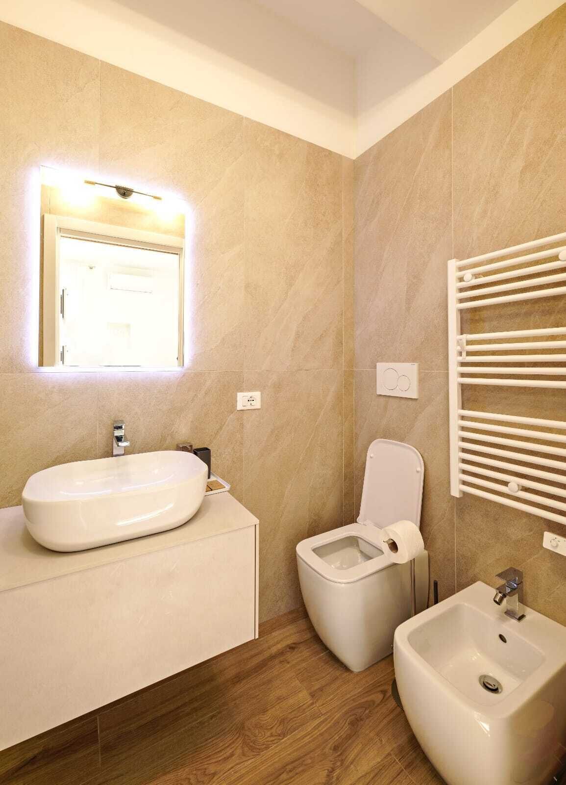 A modern bathroom with a large sink, a toilet, and a bidet.