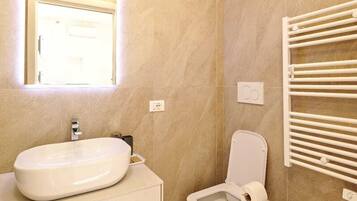 A modern bathroom with a large sink, a toilet, and a bidet.