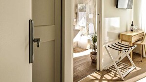 Een modern interieur met een houten vloer, een witte deur, een flatscreen-televisie aan de muur en een kleine houten tafel met stoelen.