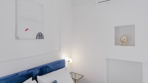 Een slaapkamer met een bed, een wandairconditioner, een klein decoratief object en een kunstwerk aan de muur.