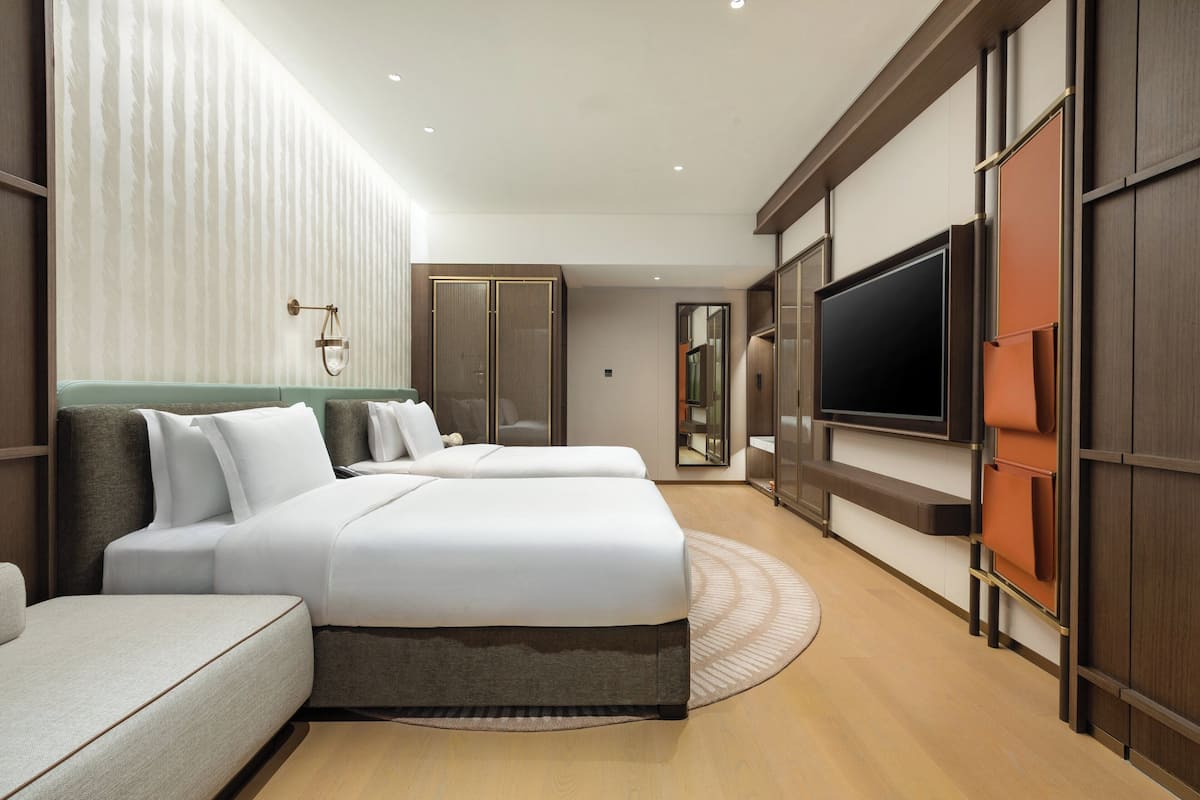 A modern hotel room with a large bed, a sofa, a TV, and a wardrobe.