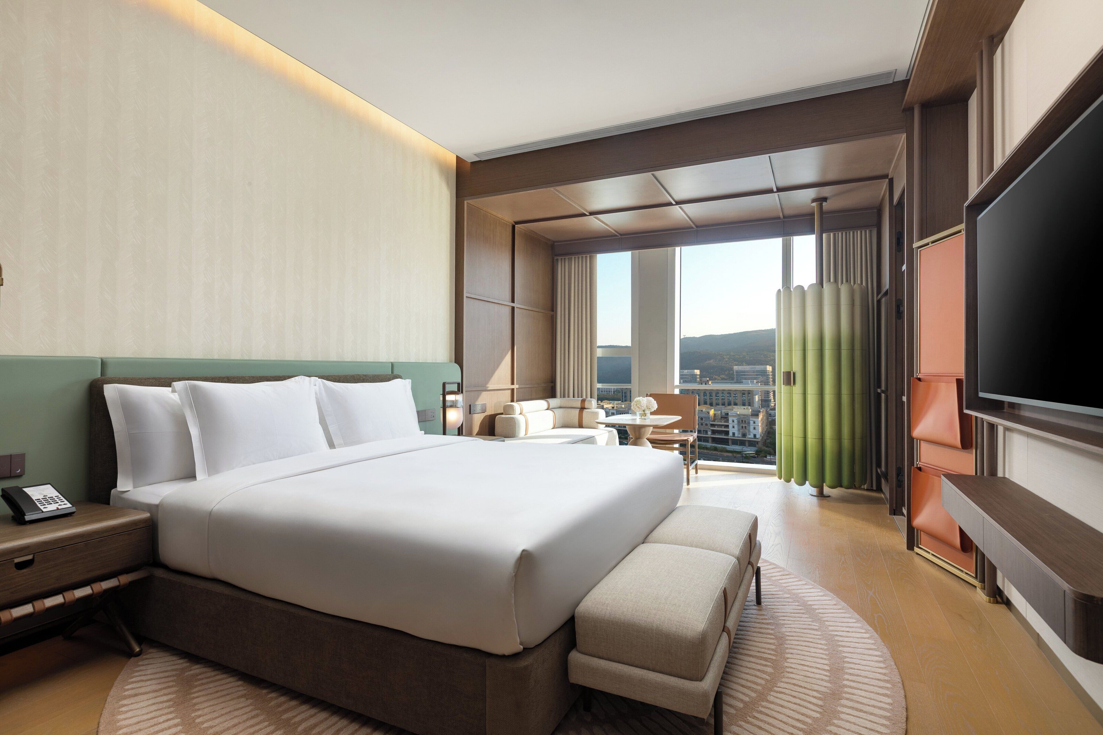Una habitación de hotel moderna con una cama grande, un televisor de pantalla plana, un escritorio y vistas a la ciudad.