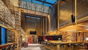 A modern bar area with a high ceiling, bar stools, and a well-lit interior. - Hotel Indigo Zhuhai Hengqin by IHG (Zhuhai)