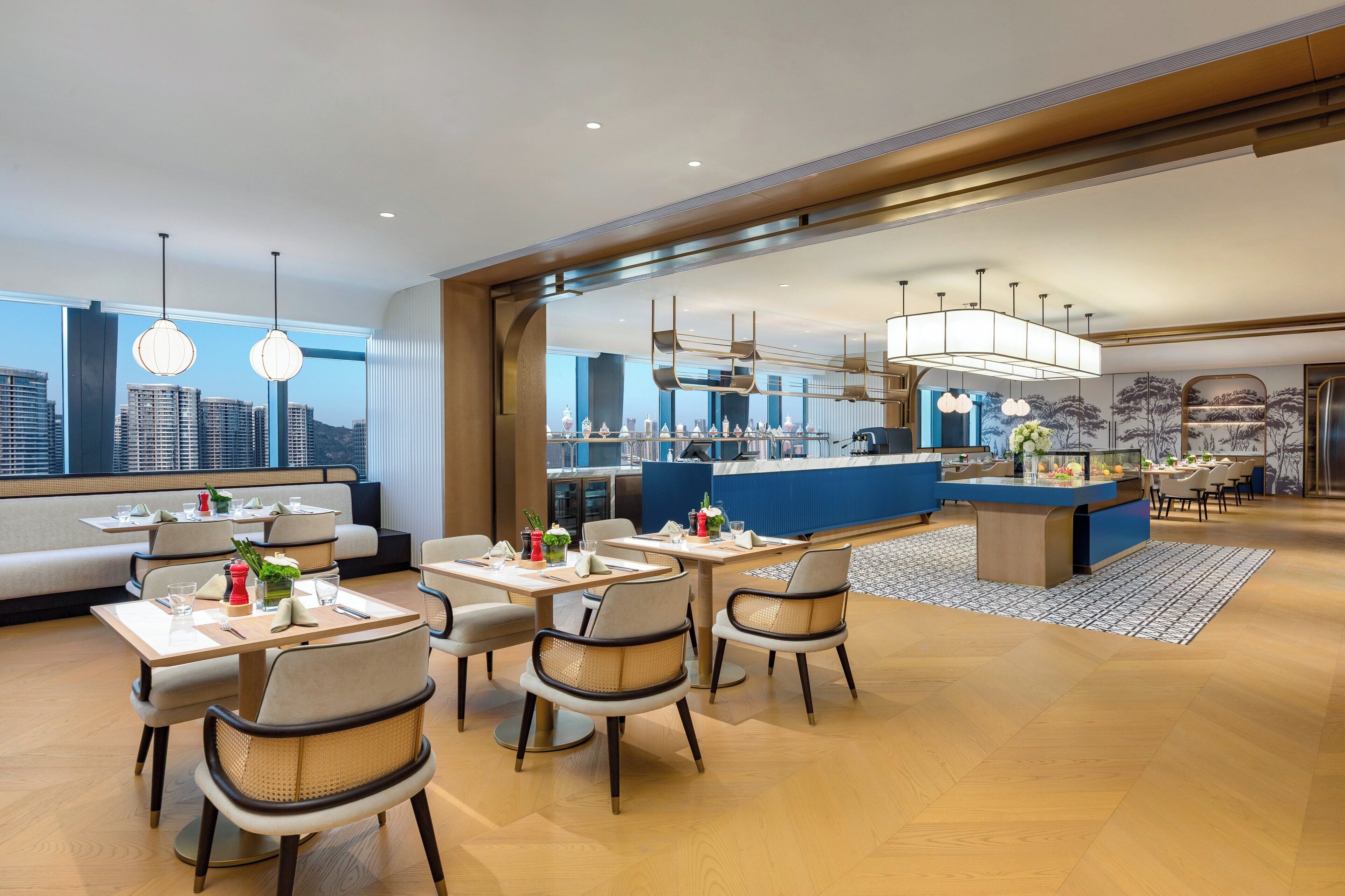 A modern hotel lobby with a seating area, a bar, and a city view.