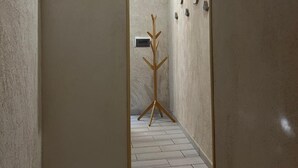 A hallway with a coat rack, a sign with the word "Love", and a wall-mounted thermostat. - The Torrione Anchor (Salerno)