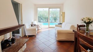 Un salón amplio con un ventanal grande, un sofá blanco, una mesita pequeña y un banco de madera.