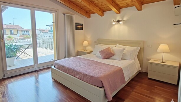 Un dormitorio con cama, dos mesitas de noche, un ventanal y vistas al exterior.