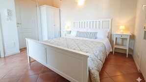 Un dormitorio con cama, mesitas de noche, armario y puerta.