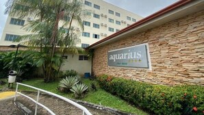 An Aquarius Aft Hotel with a stone facade, palm trees, and a well-maintained garden. - Rede Andrade Aquarius (Porto Velho)