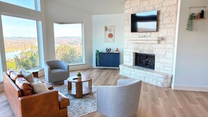 Una sala de estar moderna con chimenea, televisor grande y vistas al exterior.