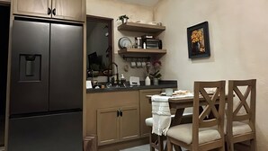 Uma cozinha compacta com geladeira, armários de madeira e um espaço de refeições com mesa e cadeiras.