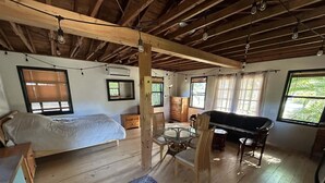 Une pièce spacieuse comprenant un lit, une table à manger avec des chaises, un canapé et une grande fenêtre laissant entrer la lumière naturelle.