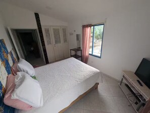 A bedroom with a bed, a desk, a TV, and a wardrobe.