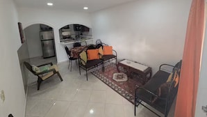 Ett kompakt bostadsutrymme med ett litet kök, en matplats med bord och stolar samt en soffa.