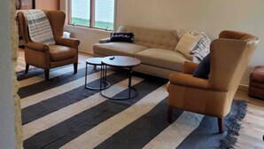 Ett vardagsrum med en soffa, två fåtöljer, ett soffbord och en randig matta.