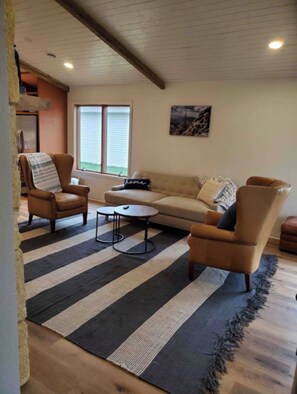 Un salon comprenant un canapé, deux fauteuils, une table basse et un tapis à rayures.