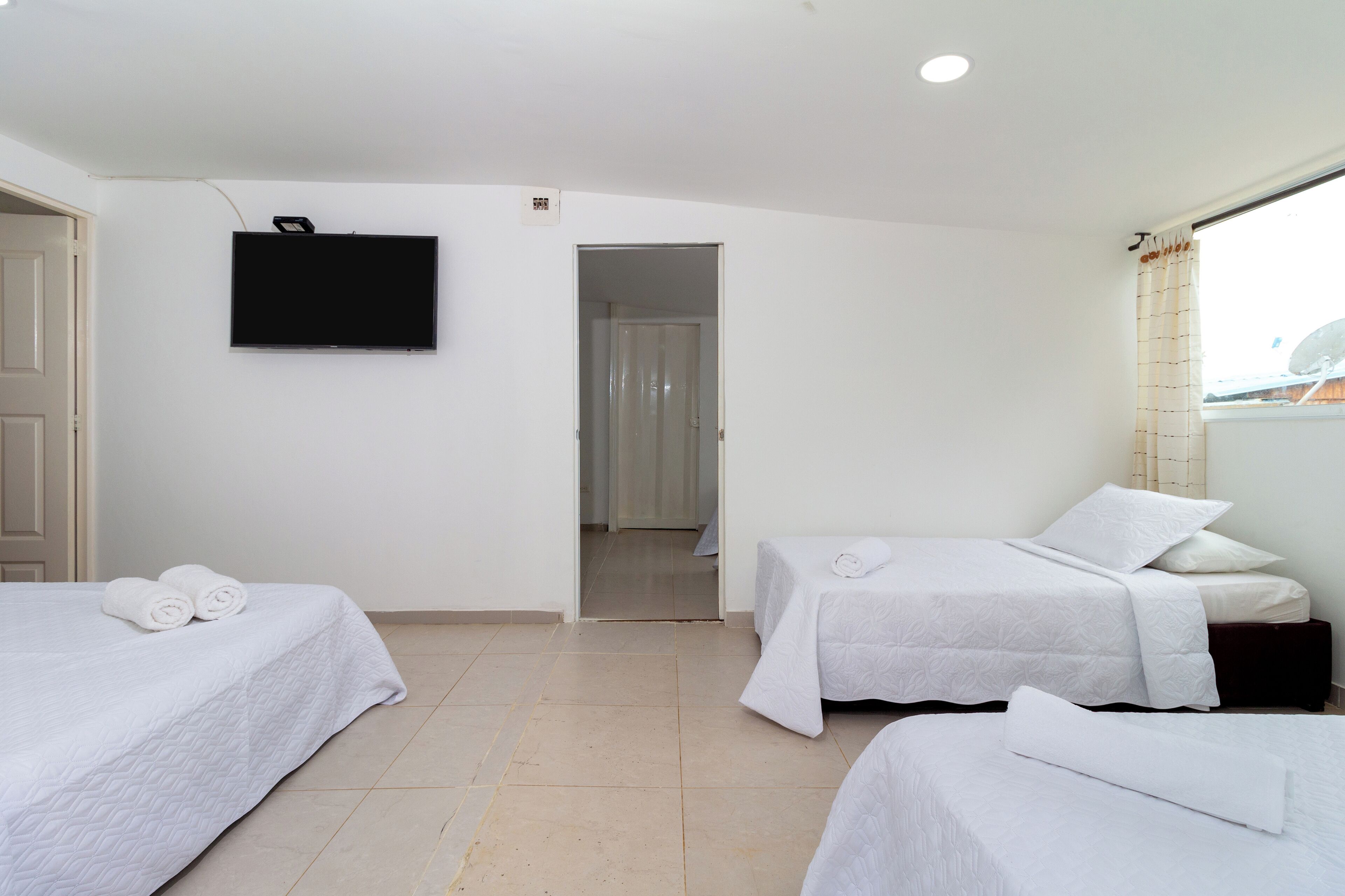 Habitación de hotel con dos camas, un televisor de pantalla plana y vista al mar a través de una ventana.