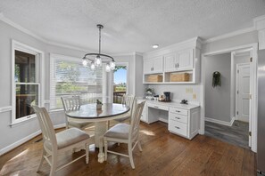 A dining area with a round table, white chairs, and a chandelier.