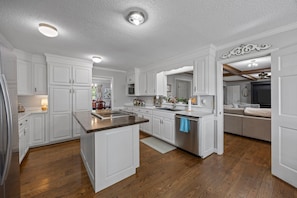 A spacious kitchen with white cabinetry, a central island, and a dining area with a sofa.