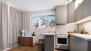 Een moderne keuken met grijze kastjes, een ingebouwde oven en een raam met uitzicht op de stad.