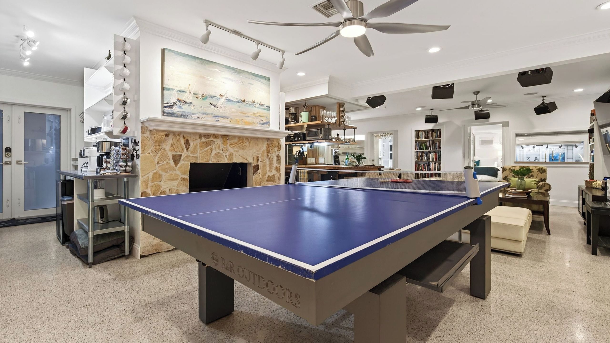 A spacious living area with a ping pong table, a fireplace, a kitchen, and a dining area.