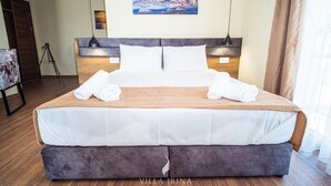Ein Hotelzimmer mit einem großen Bett, zwei Nachttischlampen, einem Bild an der Wand und Holzboden.
