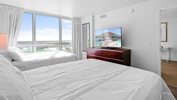 Une chambre d’hôtel avec deux lits, un téléviseur posé sur une commode en bois et une grande fenêtre donnant sur la ville.