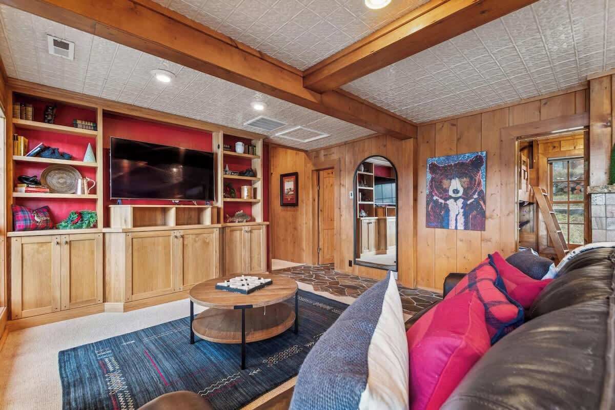A cozy living room with wooden walls, a large flat-screen TV, and a comfortable seating area with a round coffee table.