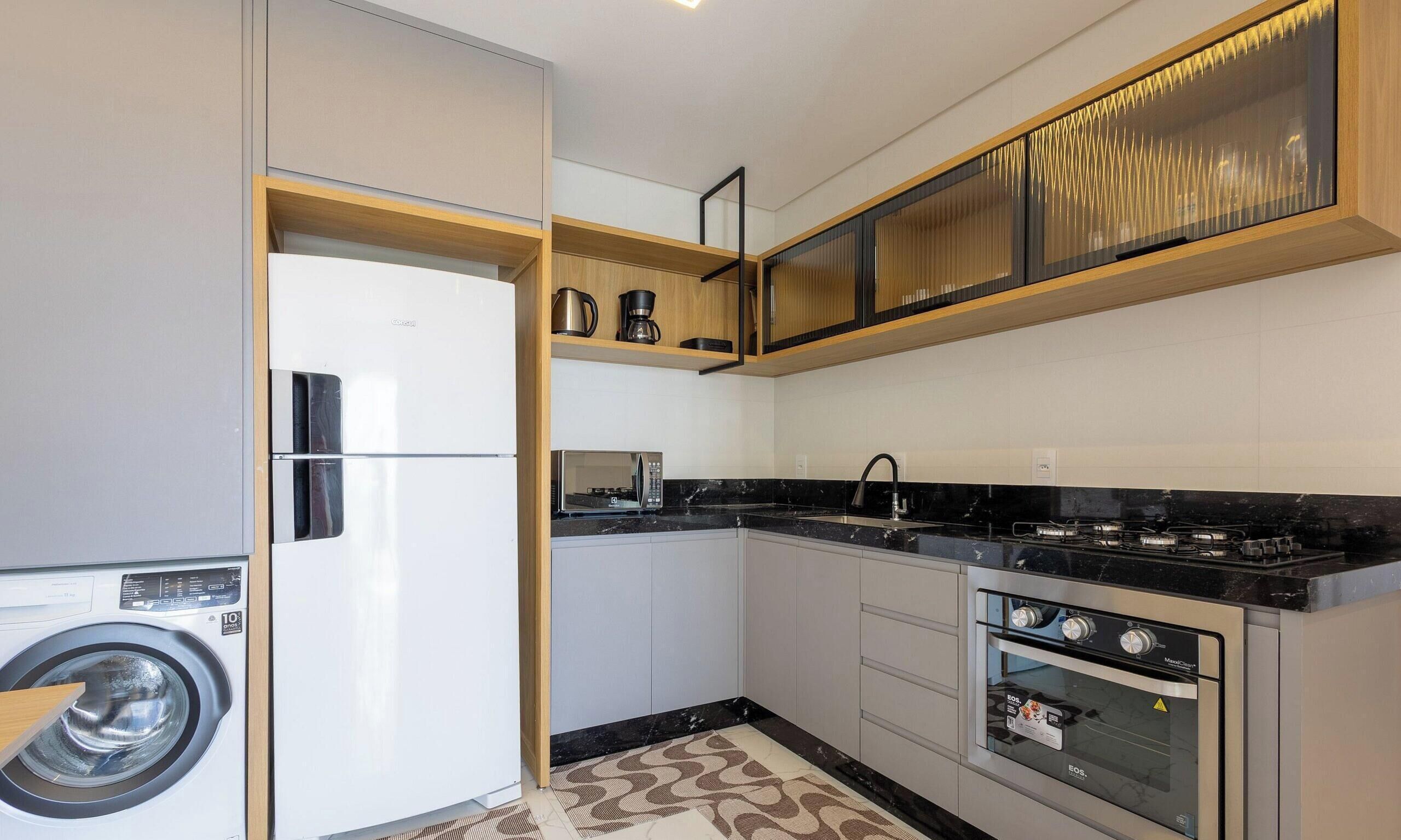 A modern kitchen with a built-in washing machine, a microwave, a stove, and a coffee maker.