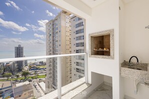 A balcony with a city view, a kitchen with a granite countertop, and a small built-in shelf. - Ocean View Apt 550m From the Beach Gev1304 (Itapema)