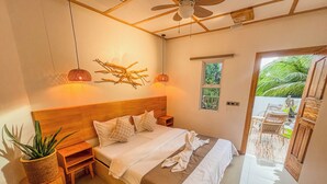 Quarto com cabeceira de madeira, cama com roupa de cama branca, ventoinha no teto e vista para o exterior.