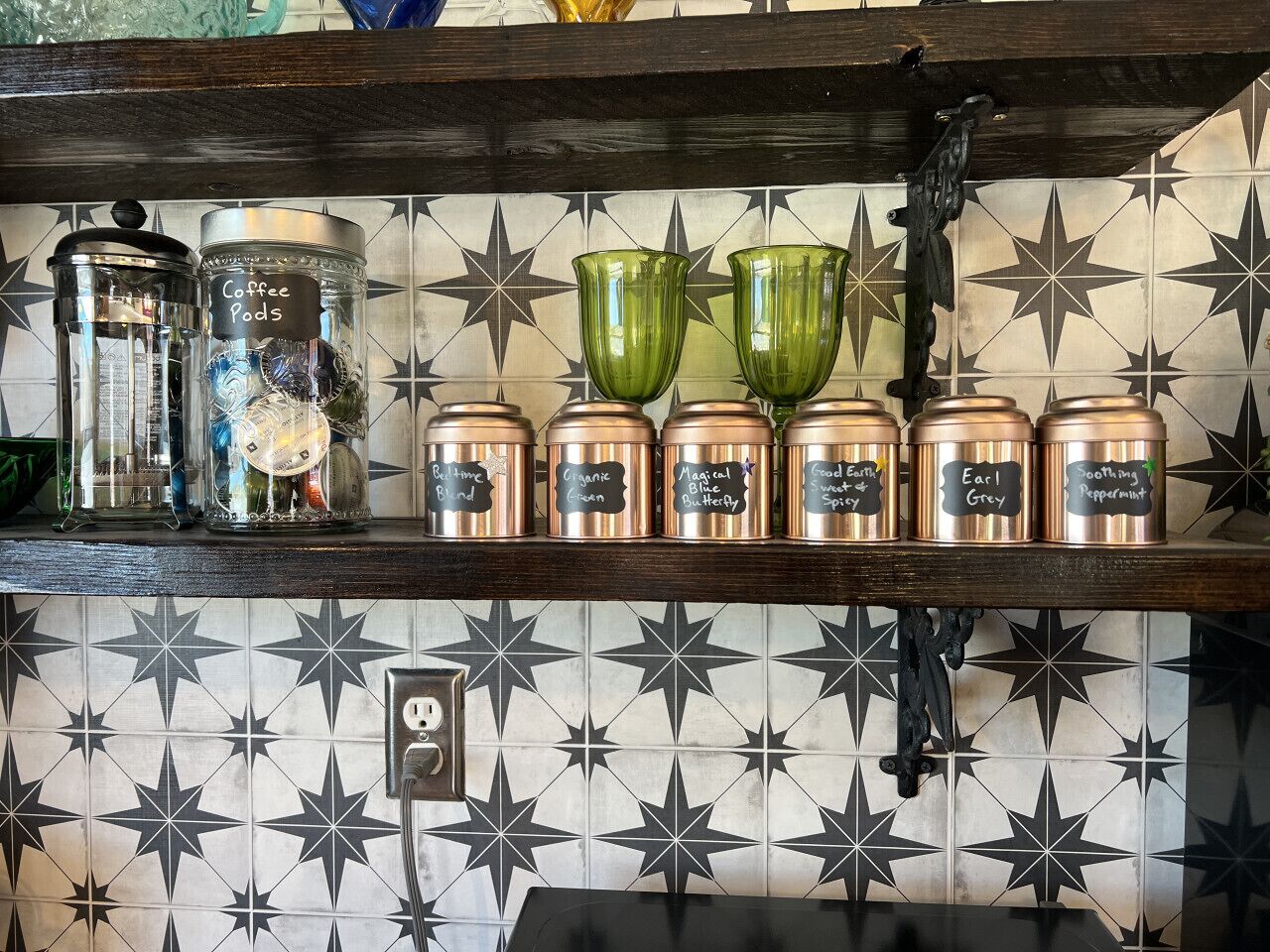 A kitchen shelf with coffee pods and spice jars labeled with names like "Earl Grey" and "Smoothing Peppermint."