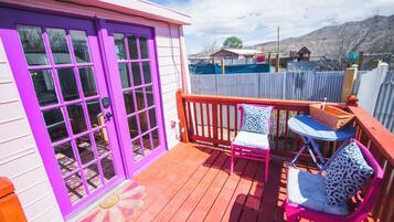 A wooden deck with a purple door and two chairs with patterned cushions.