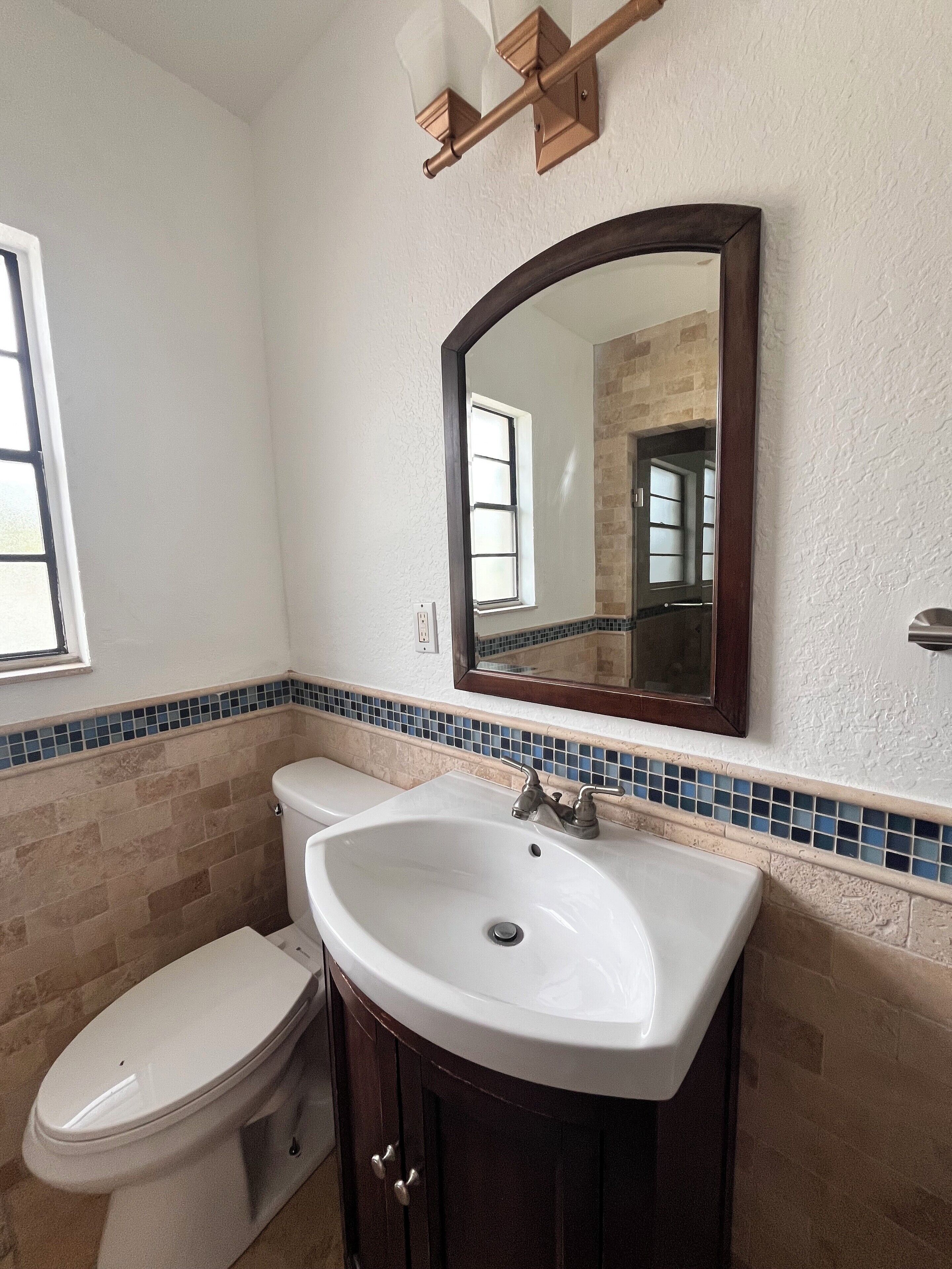 A bathroom with a toilet, sink, and mirror.