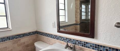 A bathroom with a toilet, sink, and mirror.