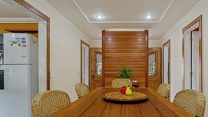 A dining area with a wooden table, wicker chairs, and a refrigerator. - Casa Confortável em Angra do Reis Proximo a Praia (Angra dos Reis)