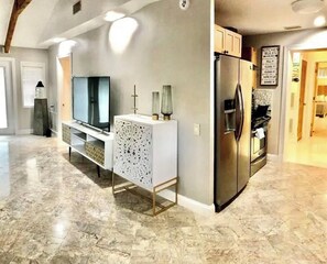 A modern kitchen with a built-in refrigerator, a TV, and a white console table with decorative items. - 2-ensuite bedrooms detached beach house& yard in superb Delray 1 milefrom beach (Delray Beach)