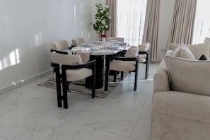 A dining area with a round table set for six, surrounded by six chairs.