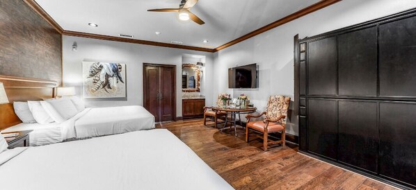 A hotel room with a large bed, a desk with a chair, a dining table with chairs, and a TV mounted on the wall. - Rough Creek Lodge Ranch and Resort (Glen Rose)
