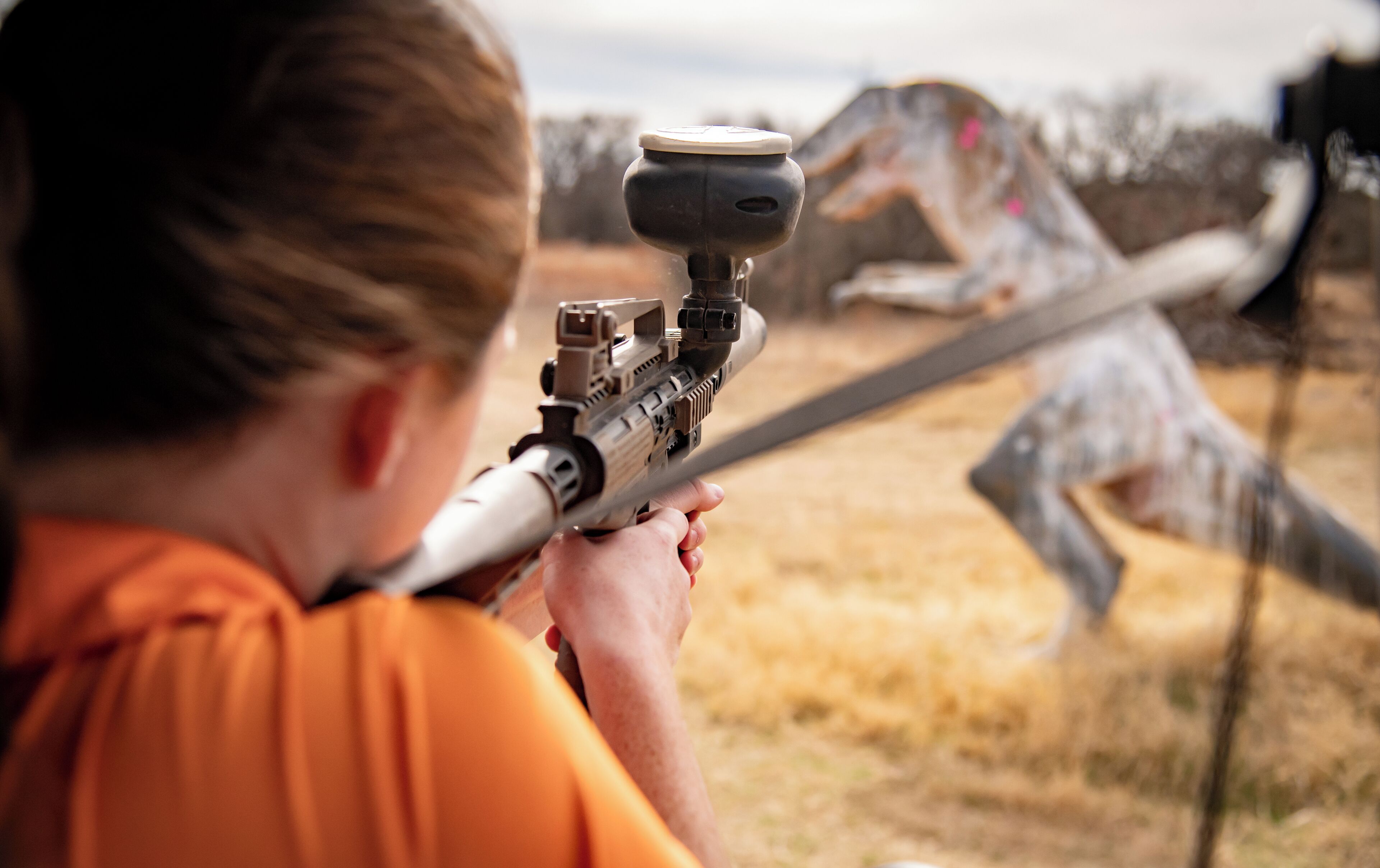 A person aiming a rifle with a scope.