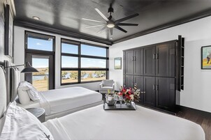 Un dormitorio con una cama grande, ventilador de techo, vistas al exterior y un minibar.