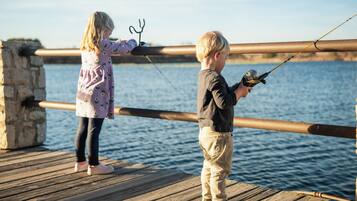 Two children fishing on a wooden pier with a view of the water.