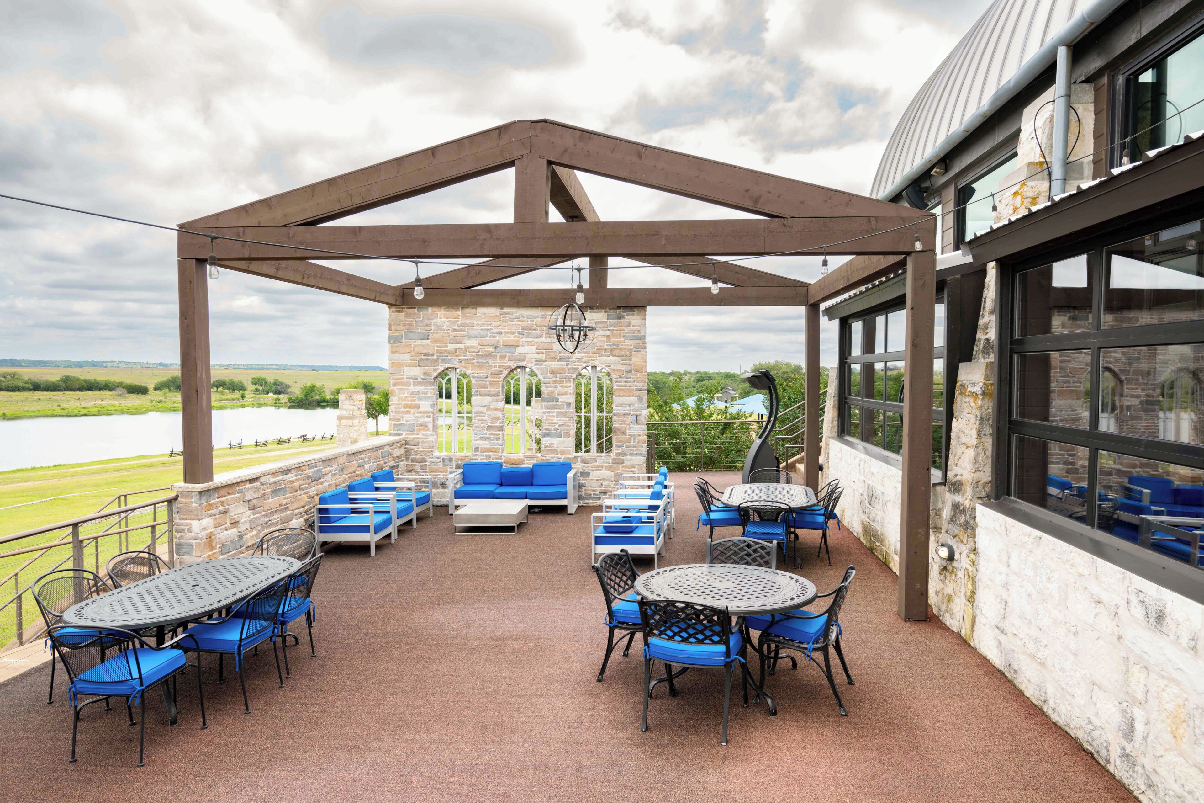 An outdoor patio with stone walls, blue seating, and tables.