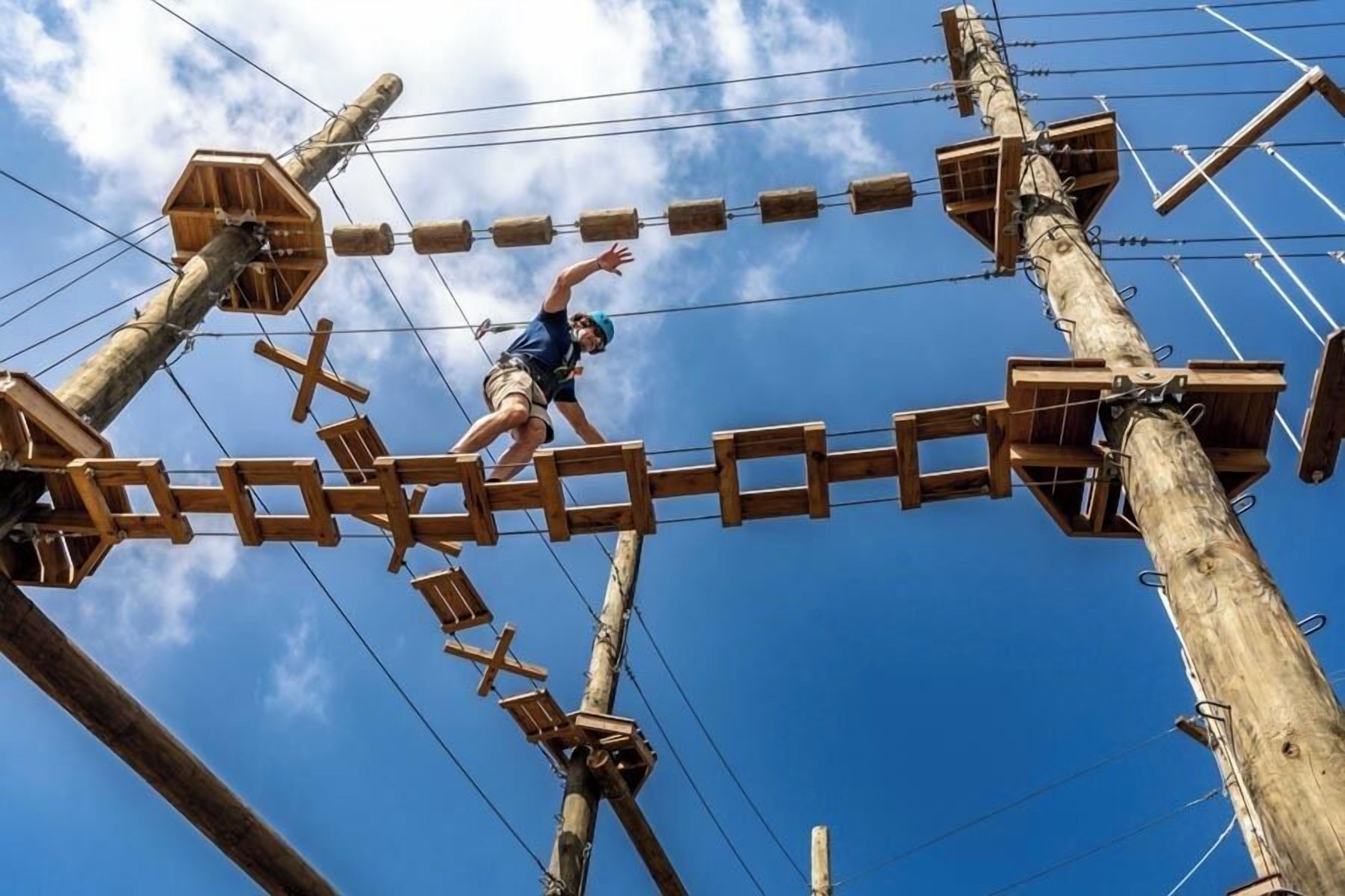 Une personne qui se déplace sur un parcours d’obstacles en bois, composé de différentes structures et de poteaux.