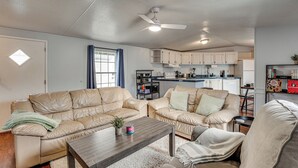 Un salon avec deux canapés en cuir beige, une table basse en bois et un ventilateur de plafond.