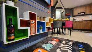 Una cocina moderna con un mueble empotrado que exhibe diversos objetos, un comedor con sillas y una encimera de cocina.