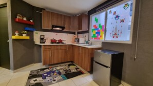 Una cocina compacta con gabinetes de madera, un refrigerador, un microondas y una cafetera.