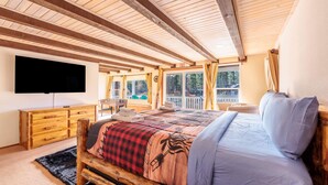 Una camera da letto accogliente con un letto grande, una testiera in legno, una televisione a schermo piatto e vista sull'esterno.